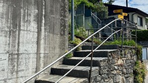 Eine Betonstairtreppe mit Metallgeländern, die an einer Steinmauer hinaufführt.