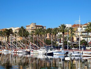 A marina with boats docked, palm trees, and buildings in the background. - in Strandnähe by Interhome (Bandol)
