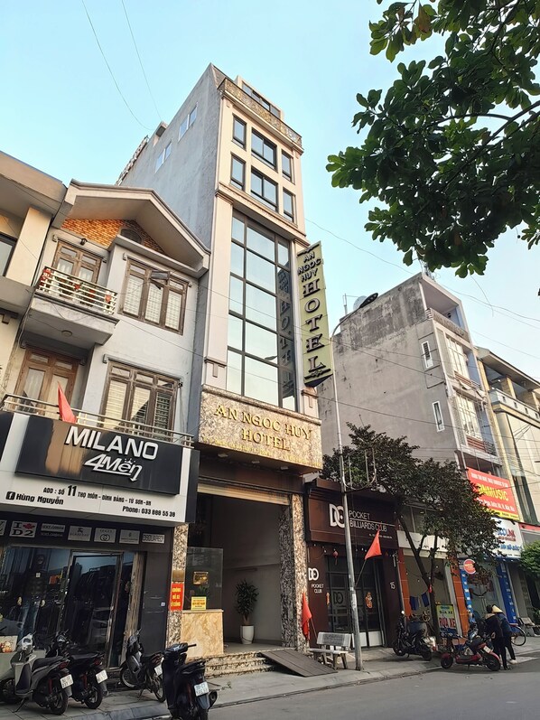 A hotel with a prominent sign, a balcony, and a storefront with a sign for a pocket billiards club. - HEYI HOTEL (Tu Son)