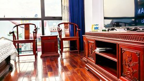 A hotel room with a large window, wooden furniture, and a flat-screen TV. - HEYI HOTEL (Tu Son)