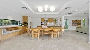 A modern kitchen with a dining area, wooden furniture, and a large window.