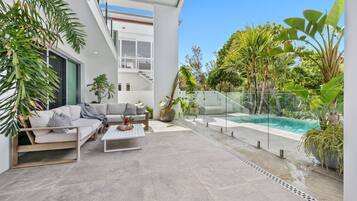 A modern outdoor living space with a pool, a sofa, and various plants.
