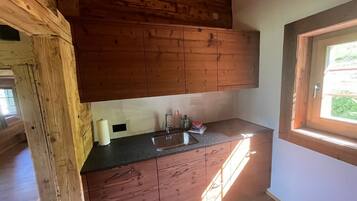 Une cuisine avec des meubles de rangement en bois, un plan de travail noir et une fenêtre.