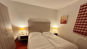 A bedroom with a bed, two bedside tables with lamps, a wardrobe, and a radiator. - Wohnung Alpinresort Kaprun top 3 by Interhome (Kaprun)
