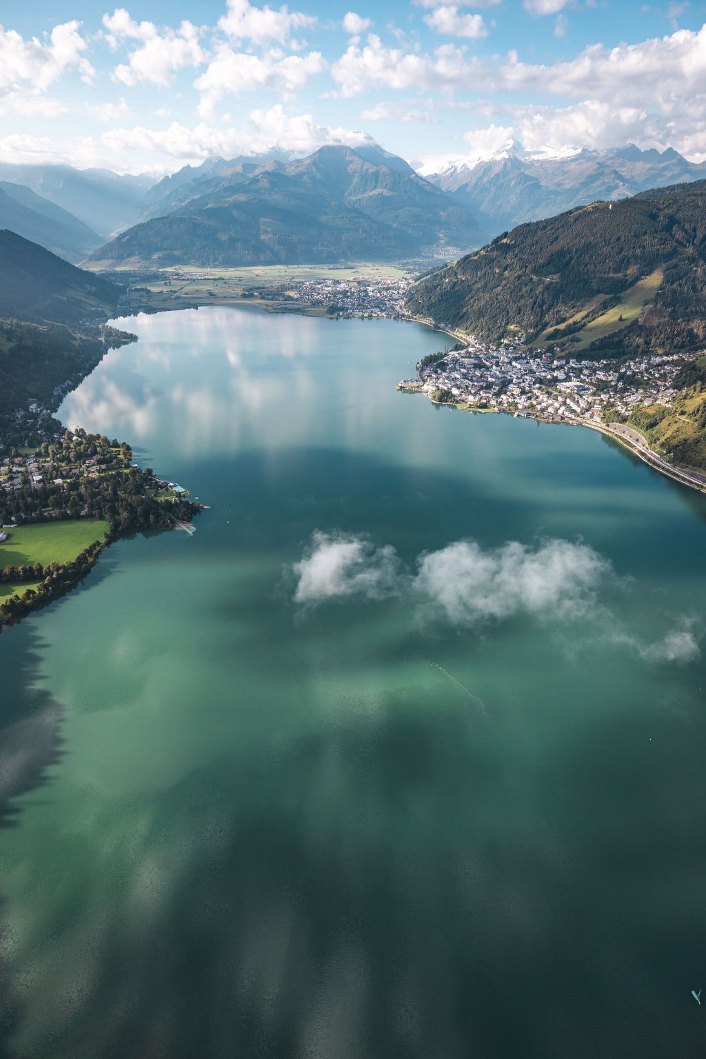 A panoramic view of a lake surrounded by mountains and a small town.