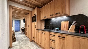 A modern kitchen with wooden cabinets, a black countertop, and a visible stove. - Grandview Collection Luxus-Wohnung in Kaprun by Interhome (Kaprun)