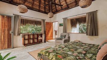Un dormitorio con cama, una silla, un estante de madera y una ventana con cortinas.