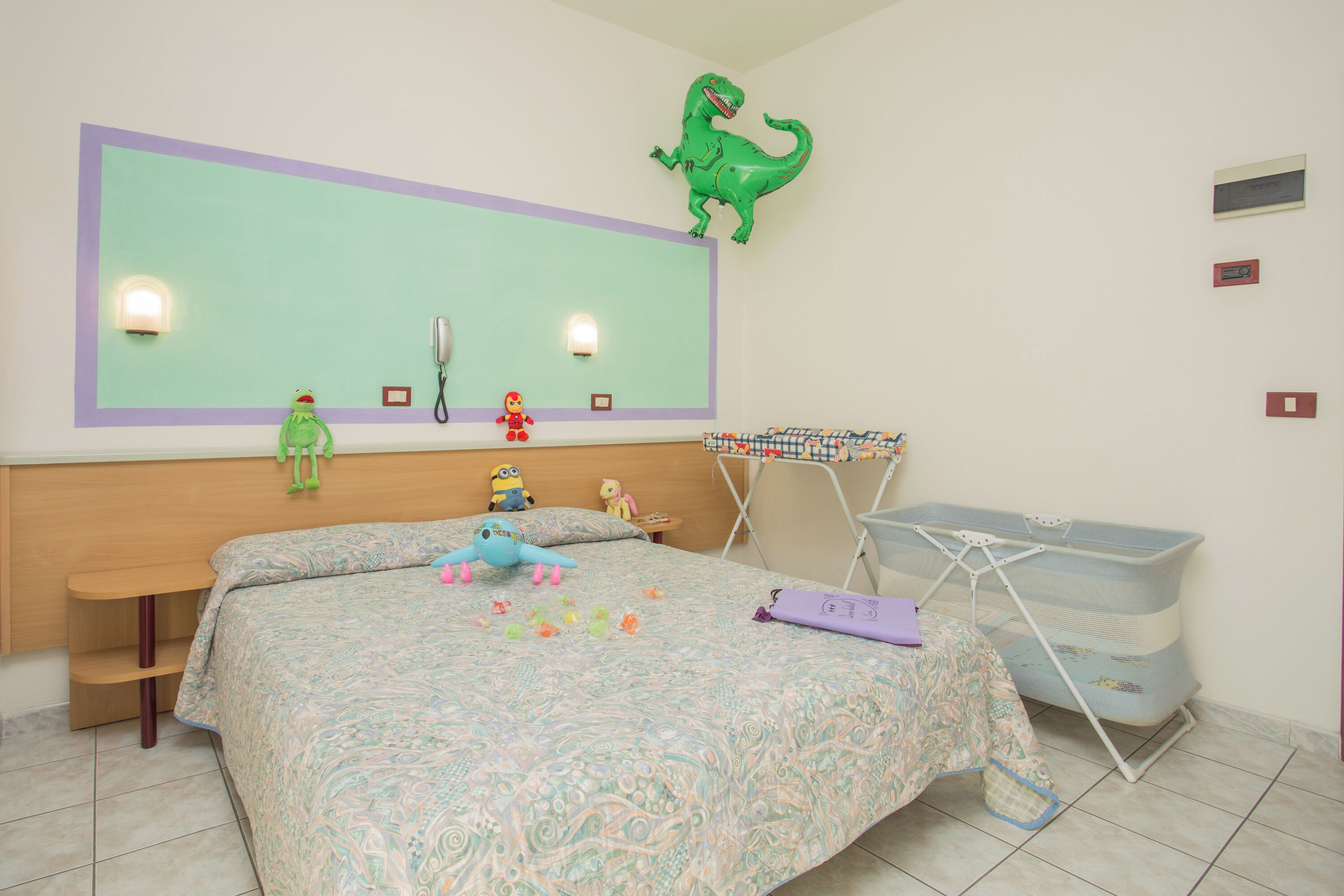 A child's bedroom with a bed, toys, a dinosaur decoration, and a laundry basket.
