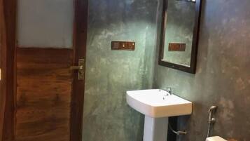 A bathroom with a wooden door, a white sink, a mirror, and a toilet.