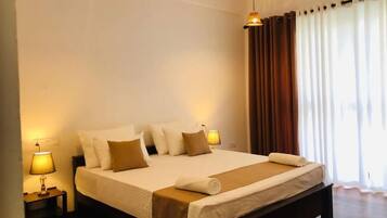 A hotel room with a large bed, two bedside lamps, a window with curtains, and a wooden floor.