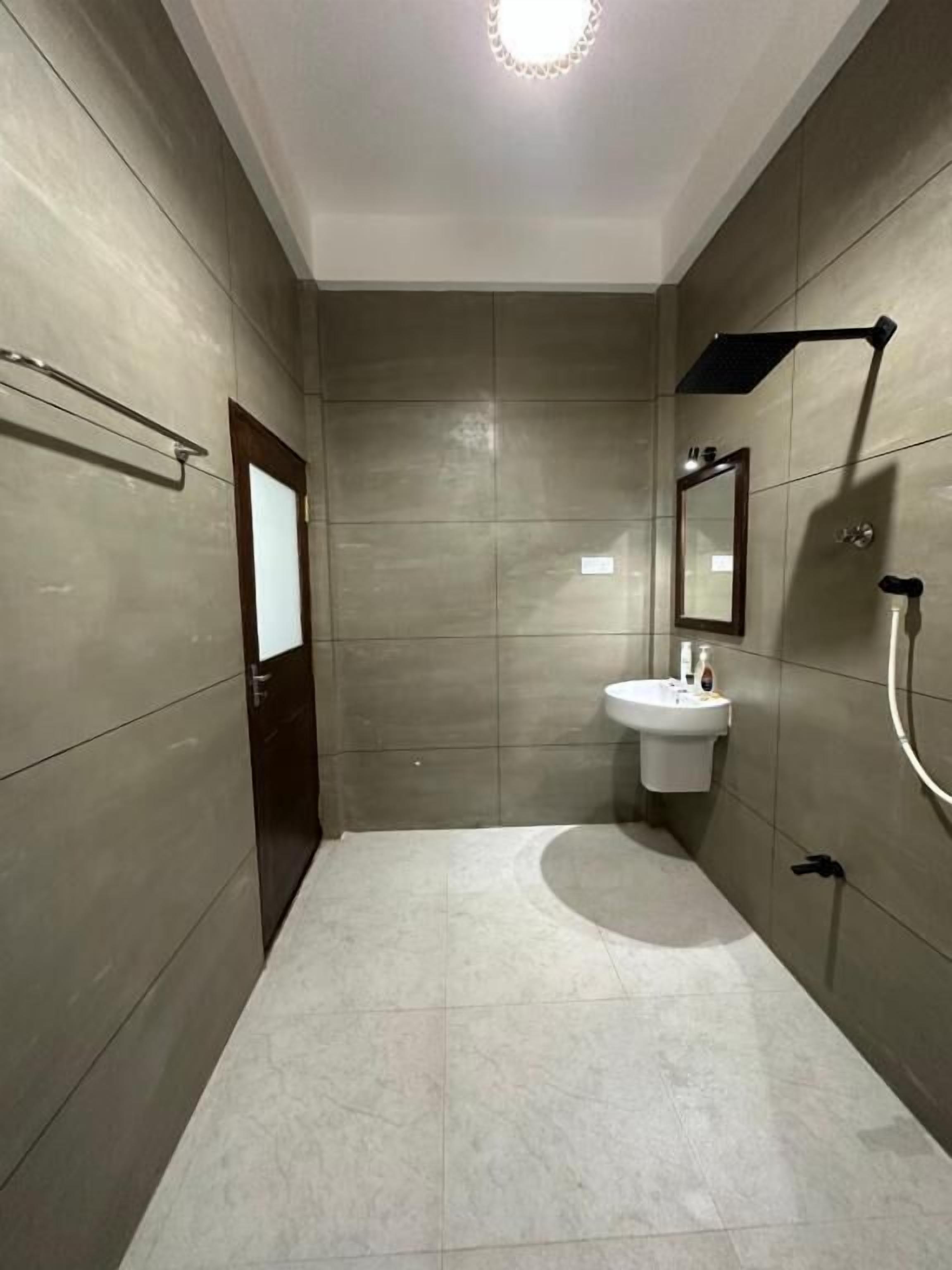 A modern bathroom with a large mirror, a sink, and a shower.