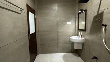 A modern bathroom with a large mirror, a sink, and a shower.