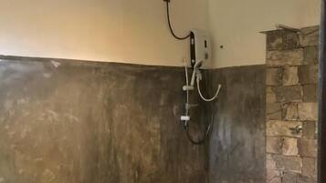 Un baño moderno con una pared de acento de piedra, un inodoro blanco y una zona de ducha.