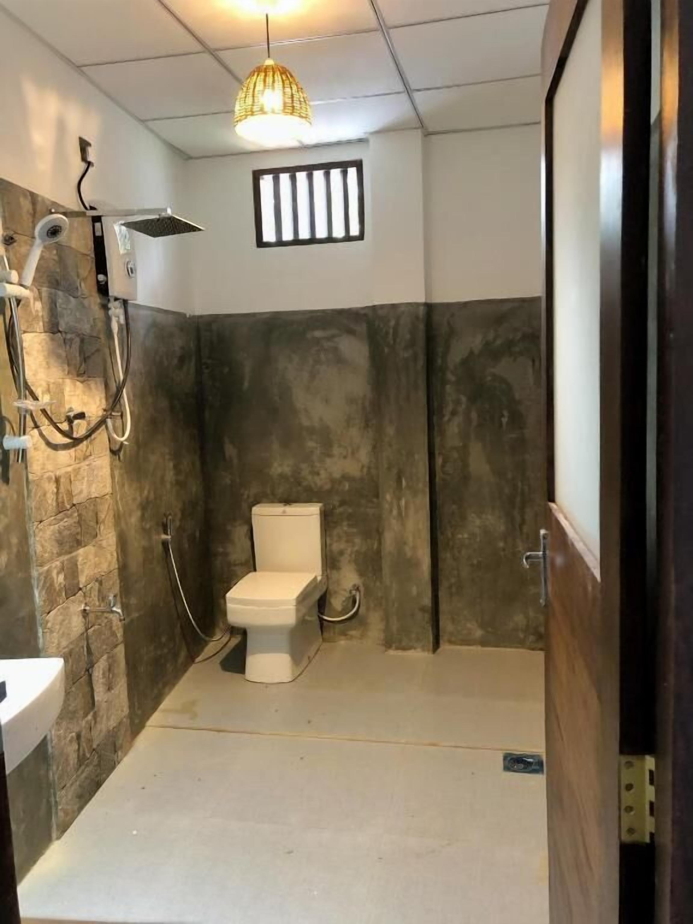 Un baño con inodoro, ducha y pared de piedra.