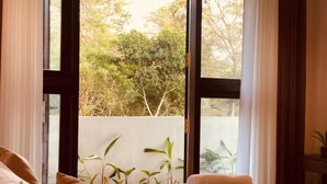 Une chambre avec une grande fenêtre, un lit avec des oreillers et une vue sur la verdure.