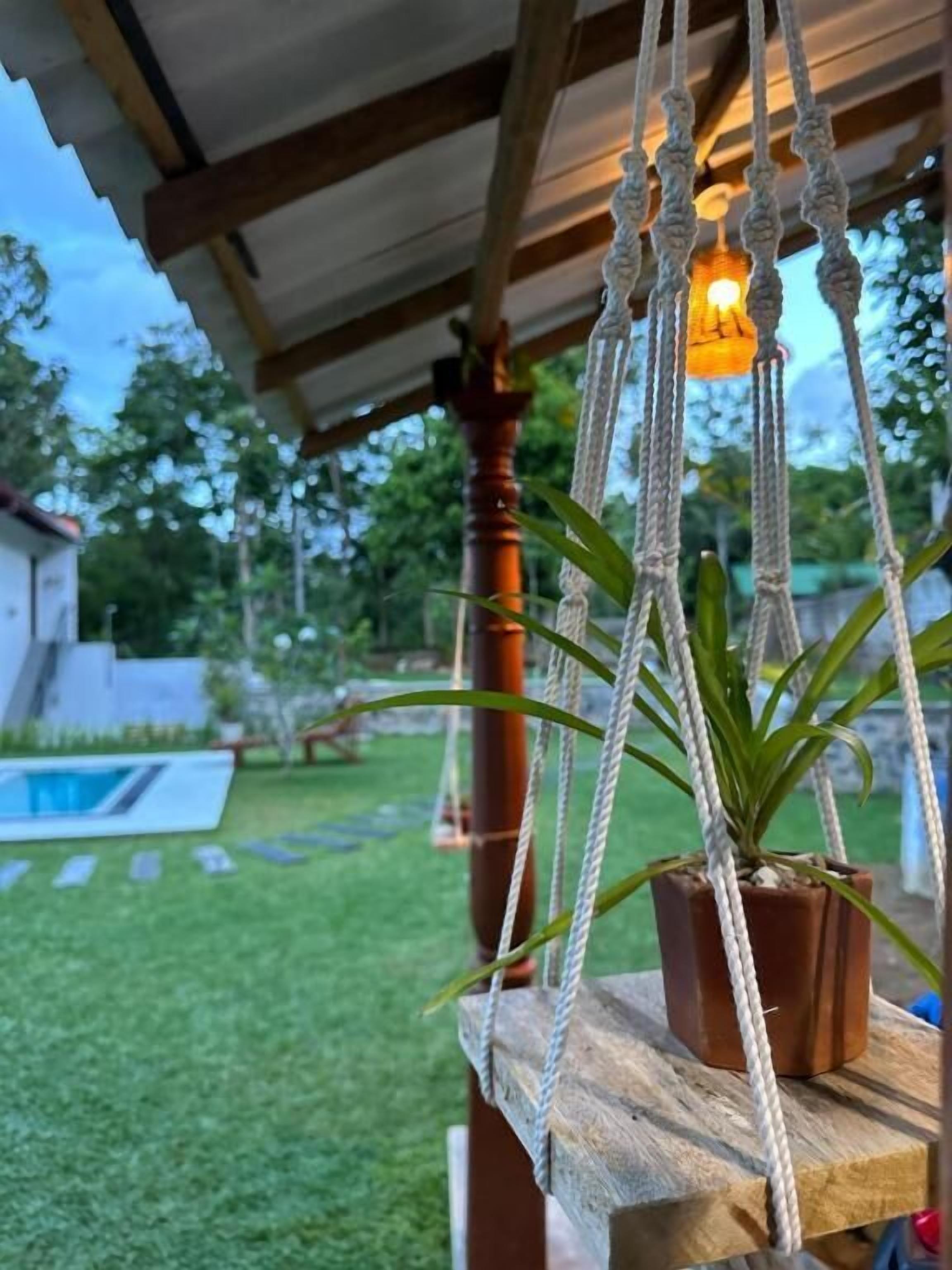 A wooden deck with a hanging macrame plant holder and a light fixture.