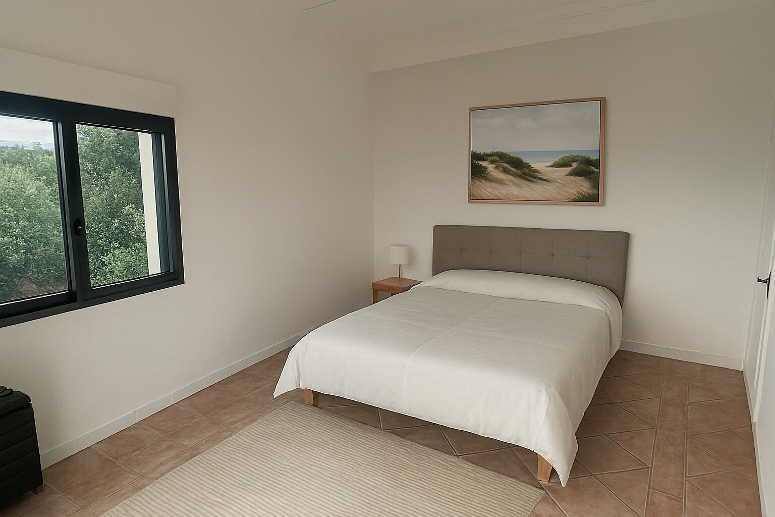 Una camera da letto con un letto, un comodino, una lampada, una finestra e un quadro appeso al muro.