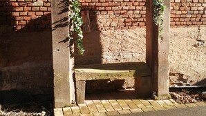 Eine Bank mit einer Backsteinmauer im Hintergrund.