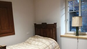 Ein Schlafzimmer mit einem Bett, einem Fenster mit Blick, einer Lampe und einer Holztür.
