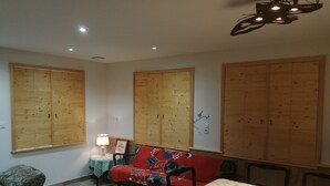 Ein Zimmer mit einem Bett, einem Tisch und einem Stuhl. An den Wänden befinden sich Holzschränke.