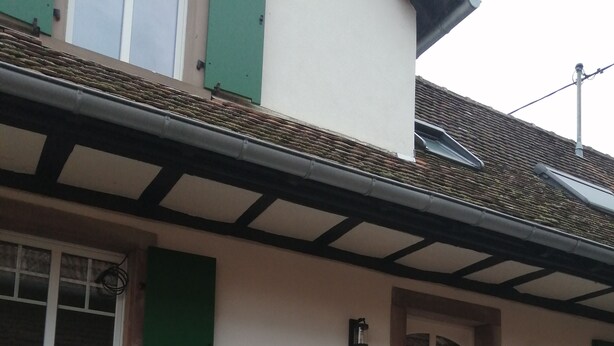 Ein Haus mit Stein Fundament, einer Holztür und einem kleinen Garten mit Stufen zum Eingang.