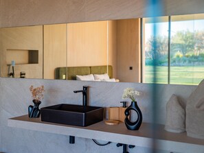A modern bathroom with a large mirror, a black sink, and a wooden vanity. - Villa Eleven Marrakech (Marrakech)