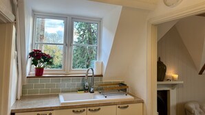 A kitchen with a window, a sink, and a clock on the wall. - Cosy one bedroom flat in a country house. (Bromham)