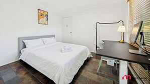 Una camera d'albergo con un letto, una scrivania, una lampada e un quadro appeso al muro.