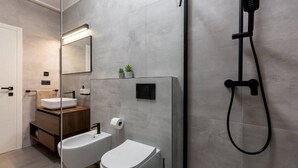 Un baño moderno con cabina de ducha de vidrio, un lavamanos blanco y un inodoro.