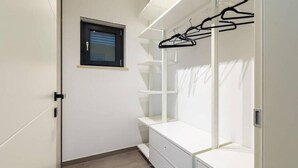 Un vestidor amplio con ventana, estantes y espacio para colgar ropa.