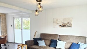 Ein Wohnzimmer mit Ecksofa, Couchtisch aus Holz und einer Pendelleuchte.