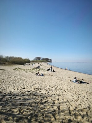 Ein Sandstrand mit Menschen, die sich sonnen und am Ufer entlanggehen.