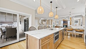 A spacious kitchen with a large island, wooden cabinets, and pendant lighting. - Summer House - Luxury 5BR w/ Heated Pool Near Beach (Ocean City)