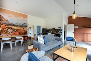 Un salon moderne avec un canapé gris, une table basse en bois et un coin repas avec des chaises blanches.