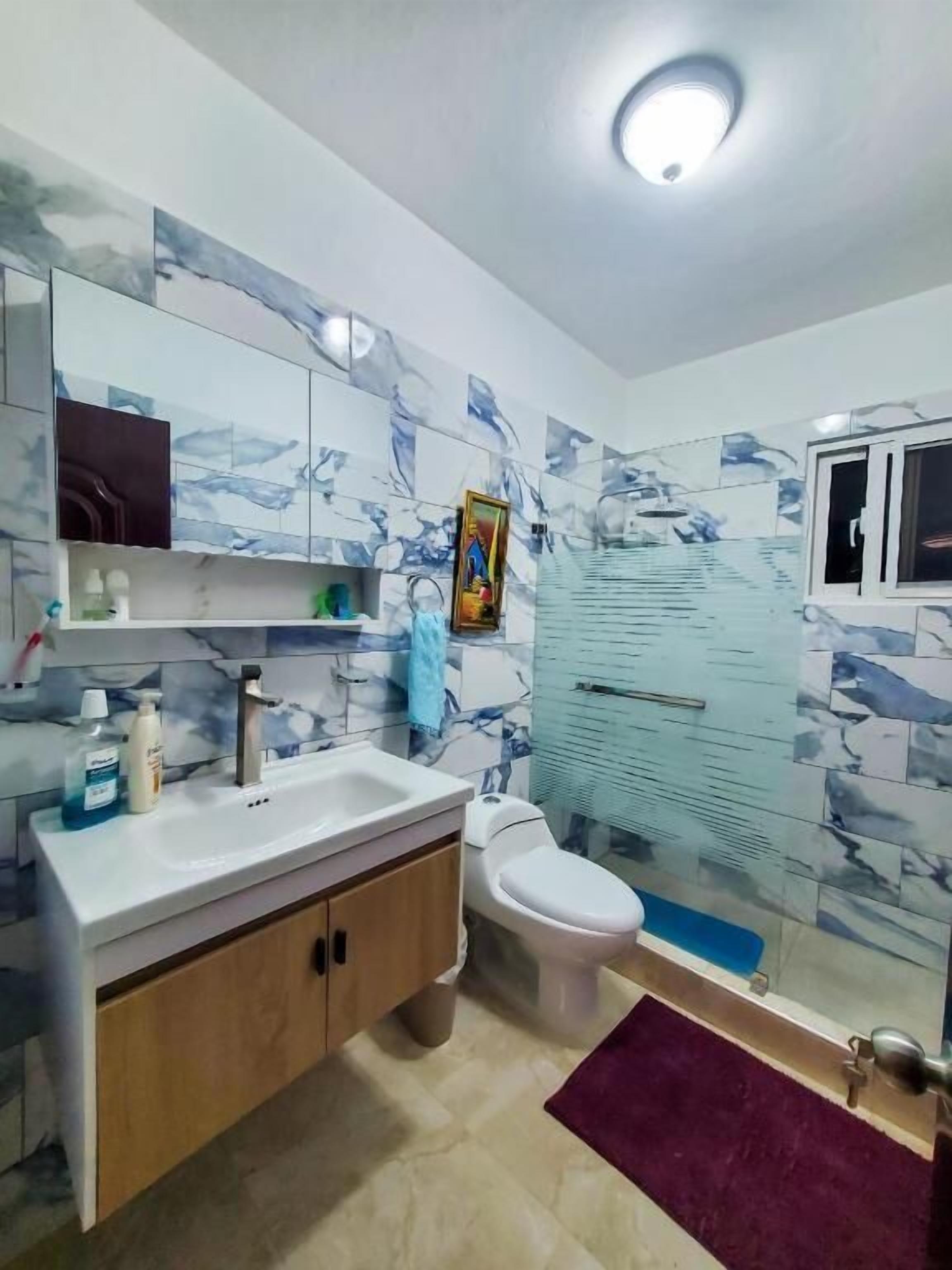 Un baño con salpicadero de mármol, un lavabo blanco, inodoro y zona de ducha.