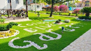 A well-maintained garden with a pathway leading to a wooden structure. - Luxury in the Caribbean (Sosúa)