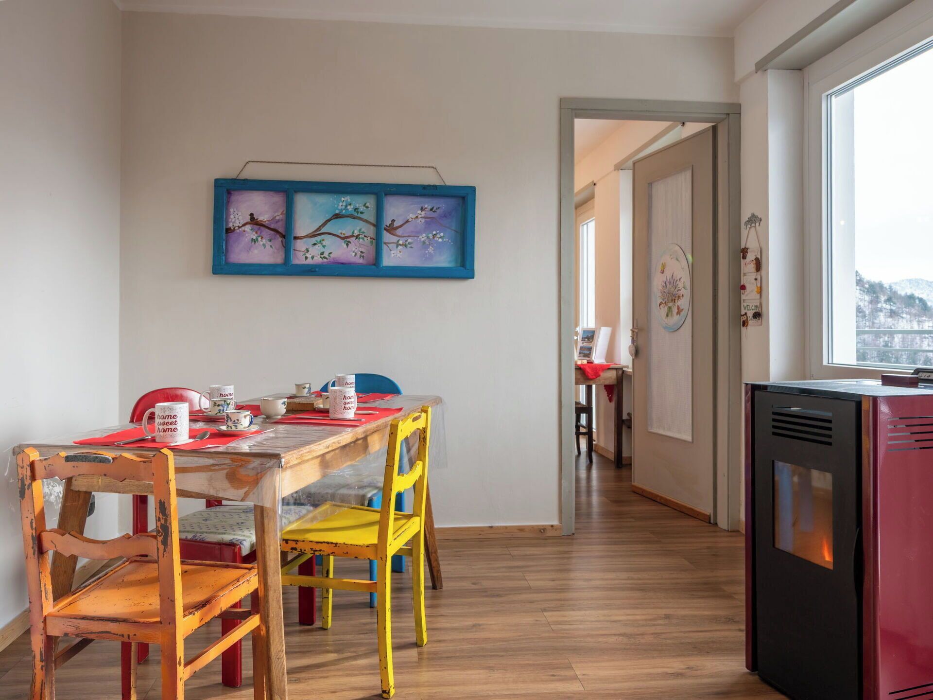 Uma sala de jantar com uma mesa de madeira, cadeiras e um quadro na parede.
