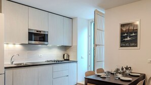 Une cuisine moderne équipée d’une cuisinière à gaz, d’un évier en acier inoxydable et de placards. Un coin repas avec une table et des chaises est également disponible.