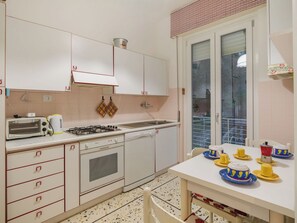 Eine Küche mit weißen Schränken, einem Gasherd, einem Geschirrspüler und einem Fenster mit Blick nach außen.
