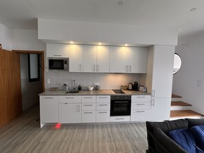 Moderni keittiö, jossa on valkoiset kaapit, mikroaaltouuni ja kahvinkeitin.