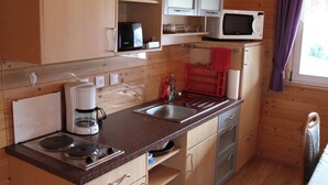 A compact kitchen with wooden cabinets, a microwave, a coffee maker, and a sink. - Holiday Home LiRa (Villach)
