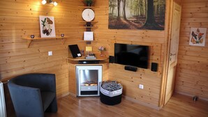 A cozy cabin interior with wooden walls, a fireplace, a television, and a clock. - Holiday Home LiRa (Villach)
