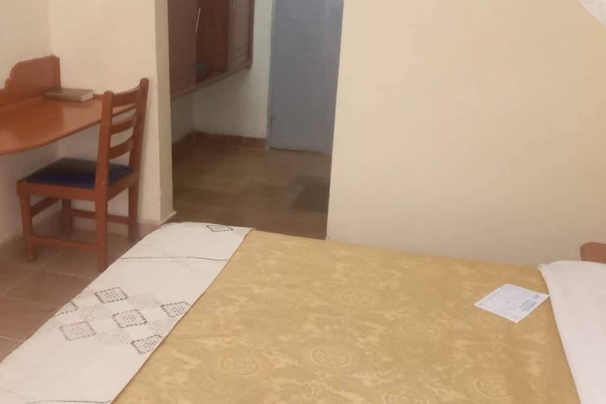 Una habitación pequeña y sencilla con una cama, un escritorio y una silla.