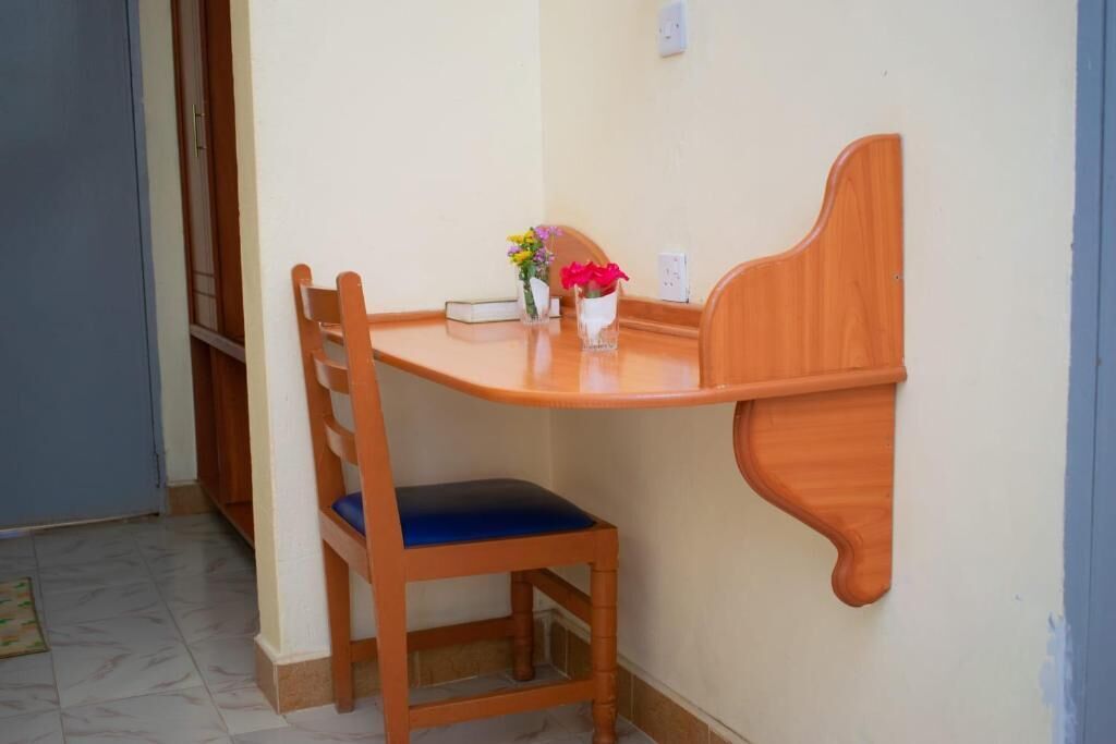 A corner dining area with a wooden table and chair, a vase with flowers, and a small book on the table.