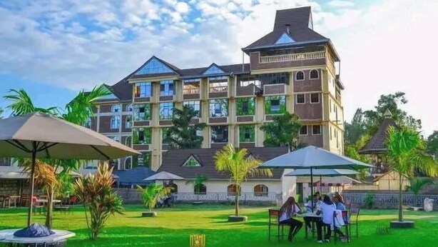 Un hotel de varios pisos con un patio central, asientos al aire libre y palmeras.