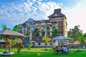 A multi-story hotel with a central courtyard, outdoor seating, and palm trees. - Bekam Hotel Kerugoya (Kerugoya)