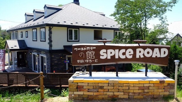 Schild mit der Aufschrift 'SPICE ROAD', im Hintergrund ein Haus.