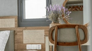 Une chambre à coucher avec une tête de lit en bois, une table de chevet avec une lampe, une chaise et une fenêtre donnant sur l’extérieur.