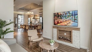 Un vaste espace de vie comprenant un coin salon avec cheminée, un coin repas et un grand tableau représentant une scène de bar.