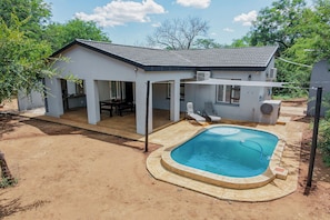 A house with a swimming pool, covered patio, and a fenced yard.